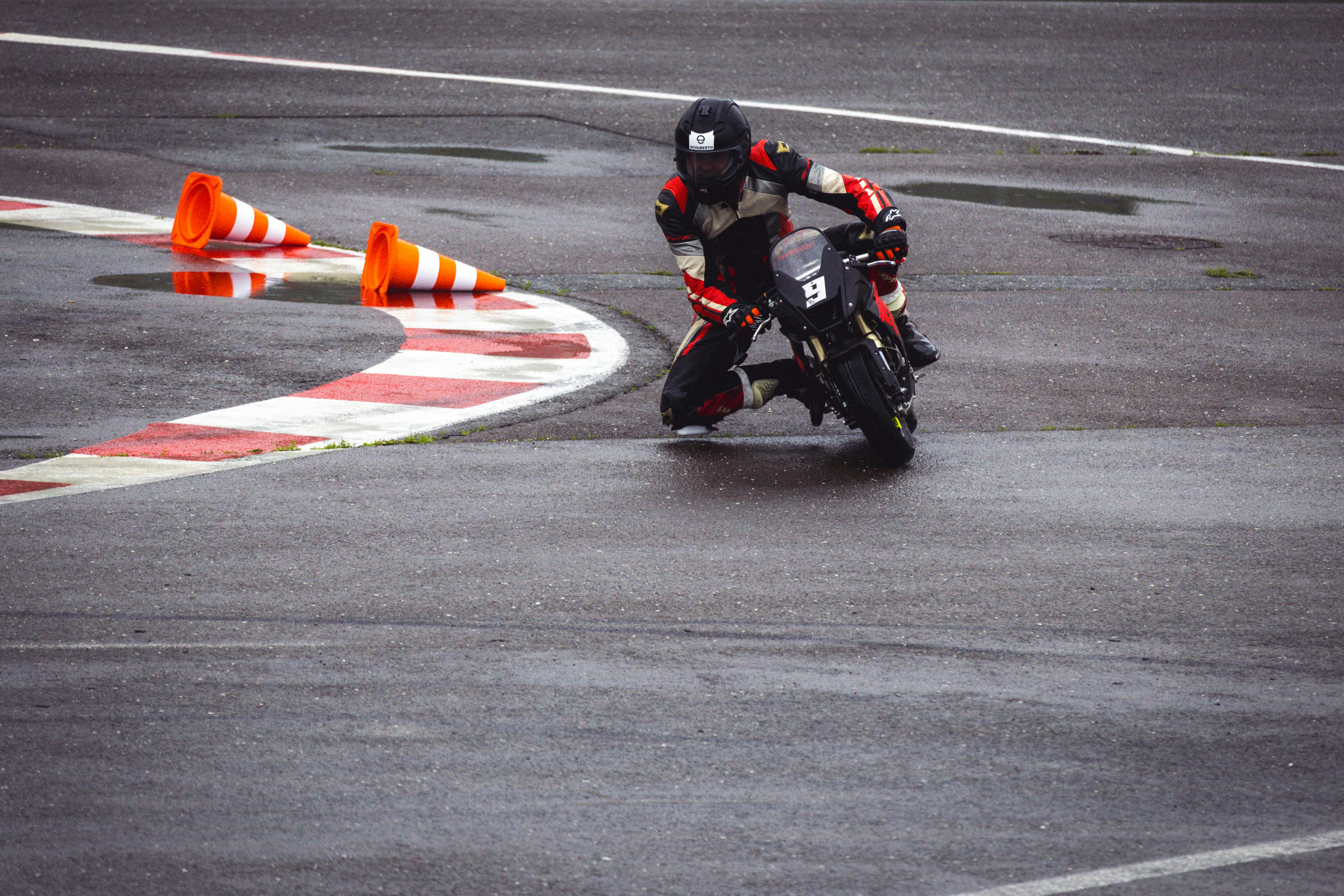 Dramatic shot of a motorcyclist expertly taking a sharp turn on a wet racing track.