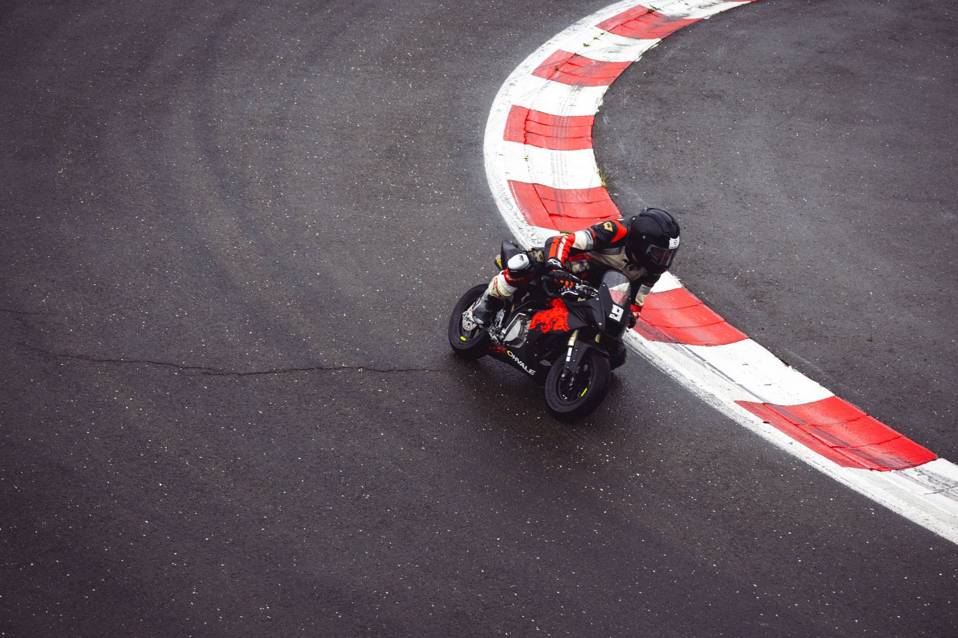 A motorcycle racer takes a sharp curve on a wet race track, showcasing speed and precision.