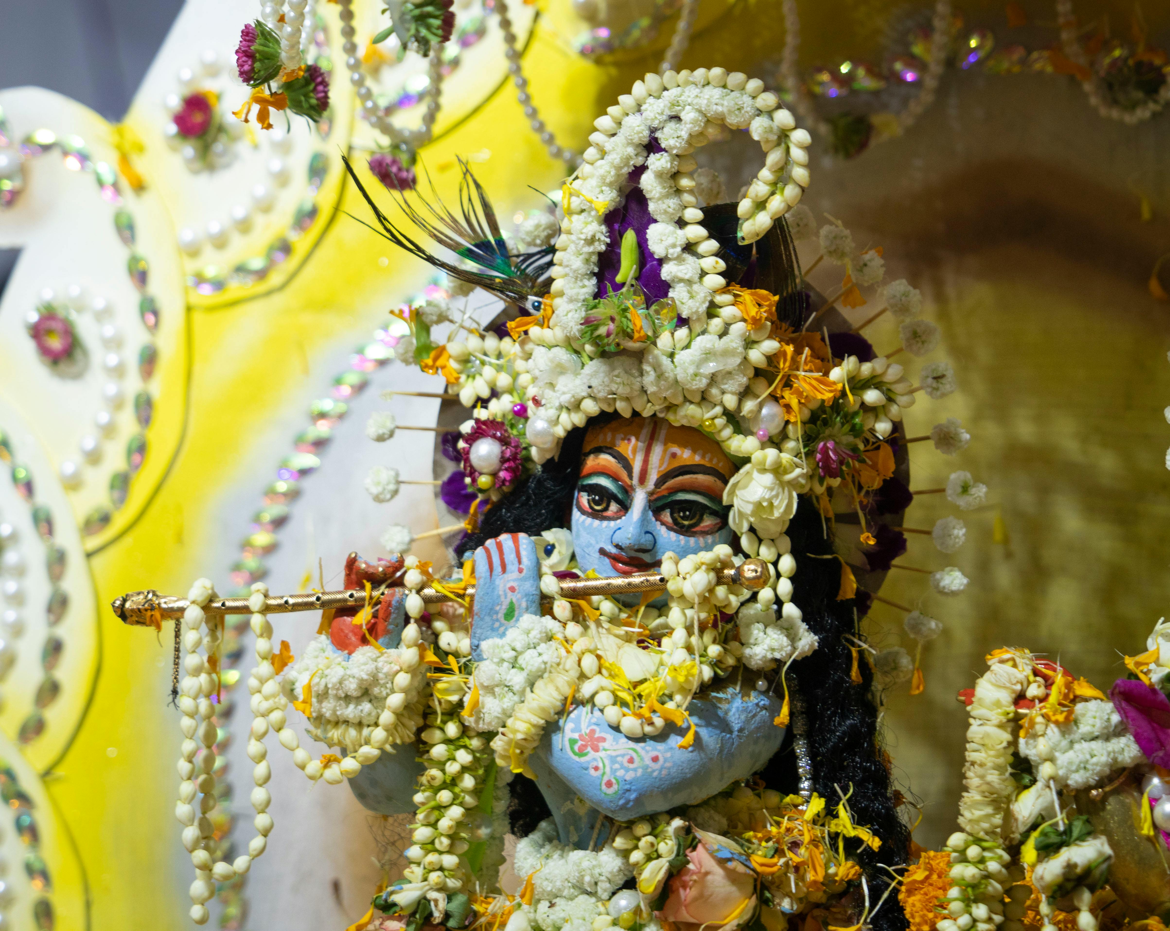Close-up of a Hindu deity sculpture adorned with intricate floral designs and vibrant colors.