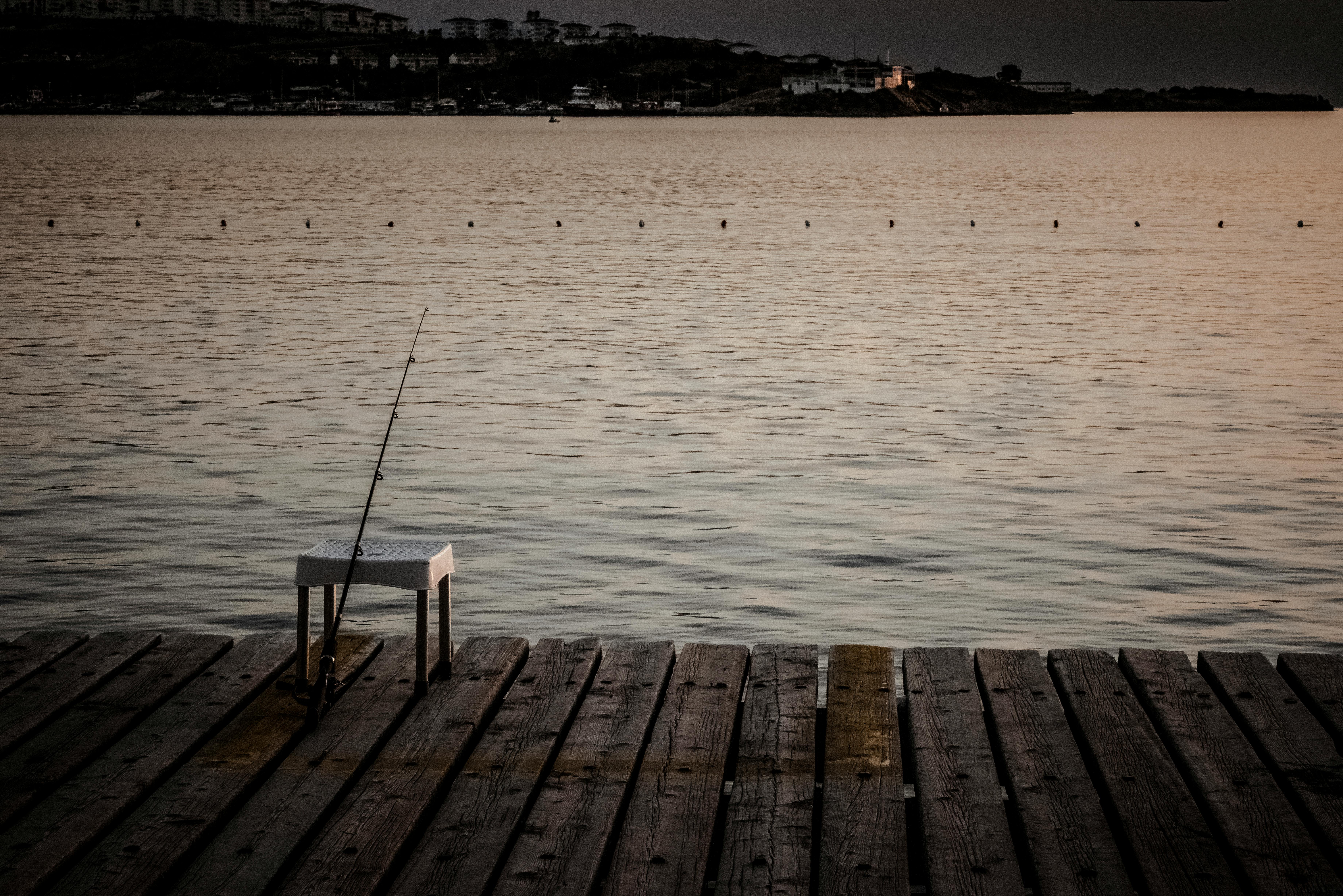 Angler standing on a wooden dock fishing into calm lake water