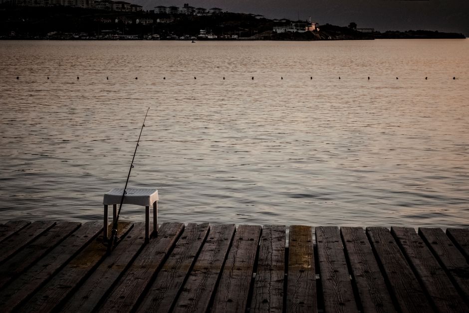 Angler standing on a wooden dock fishing into calm lake water