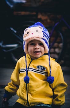 可爱的孩子戴着五颜六色的冬帽，穿着黄色夹克在户外摆姿势