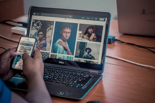 Person Holding white iphone in front of gray laptop