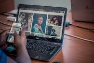 一个人在室内用戴尔笔记本电脑和智能手机查看肖像照片