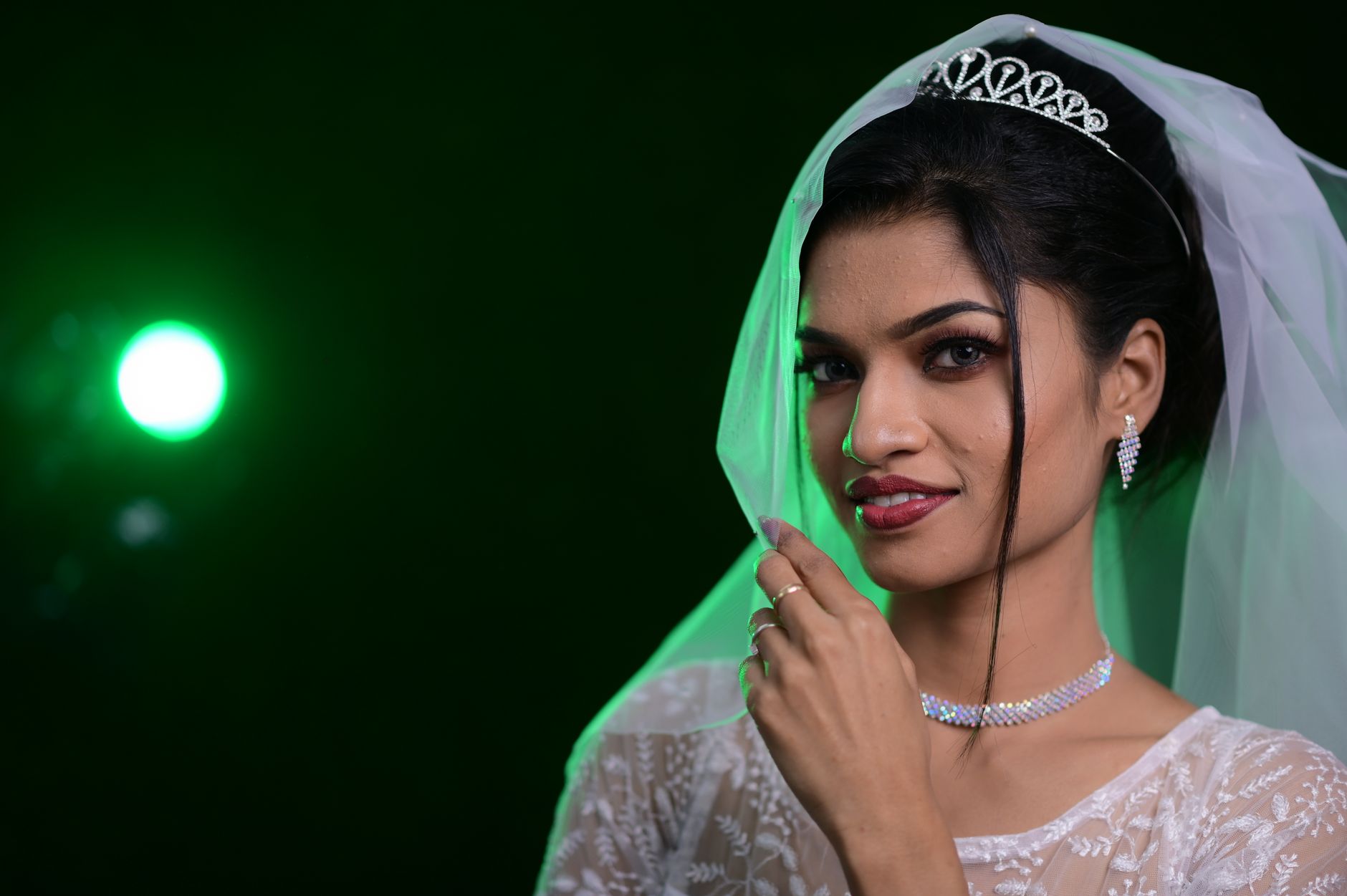 Stunning bridal portrait featuring a smiling woman with elegant jewelry and a tiara.