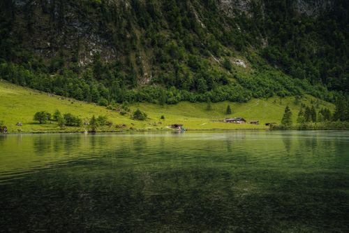 Free Peaceful summer view of a lake with lush greenery and mountain backdrop. Stock Photo