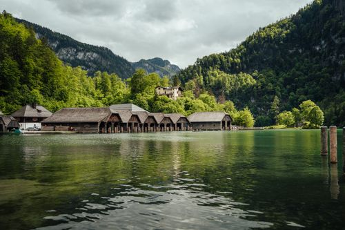Free Charming lakeside cabins surrounded by vibrant summer greenery and serene mountain views. Stock Photo
