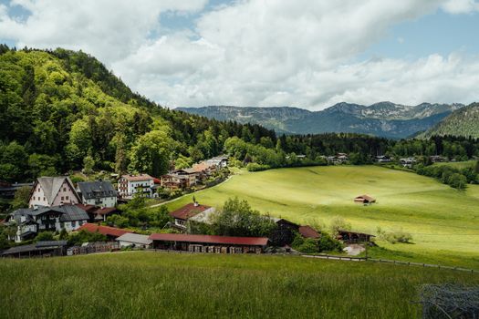 Idyllic rural landscape with lush green hills, mountains, and a charming village.