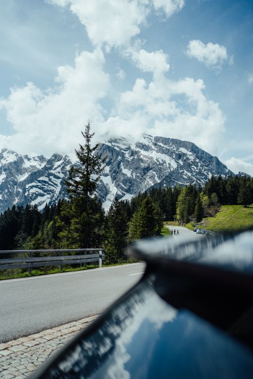 Free A breathtaking view of a winding road through snowy mountains and lush green forests. Stock Photo