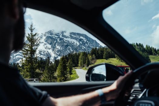 View of a snow-capped mountain from a car, depicting a scenic road trip in winter.