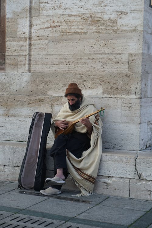 A man sitting on the ground playing a guitar