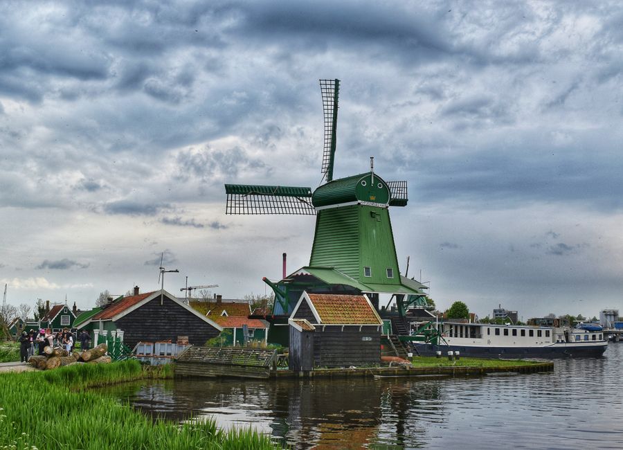 Scenic view of a traditional green windmill at Zaanse Schans under an overcast sky.