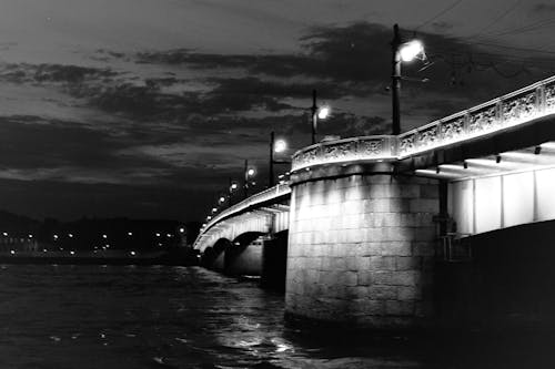 A black and white photo of a bridge at night
