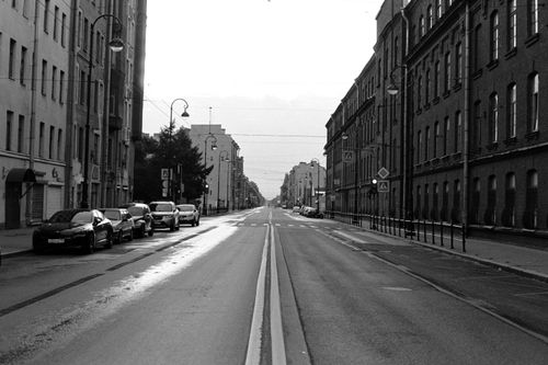 Free A classic black and white photo of an empty street in Saint Petersburg, Russia, with townhouses and parked cars. Stock Photo