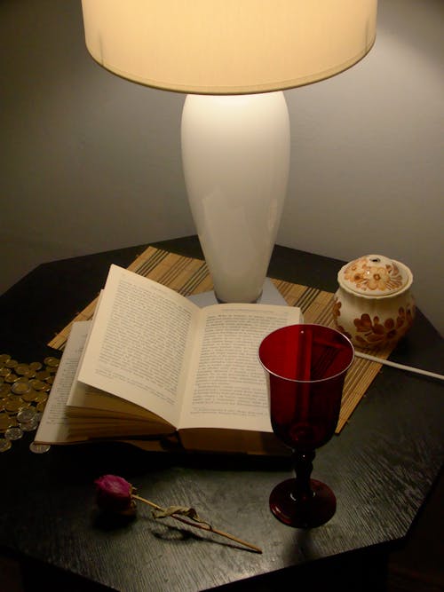 A lamp on a table with a book and a cup of coffee