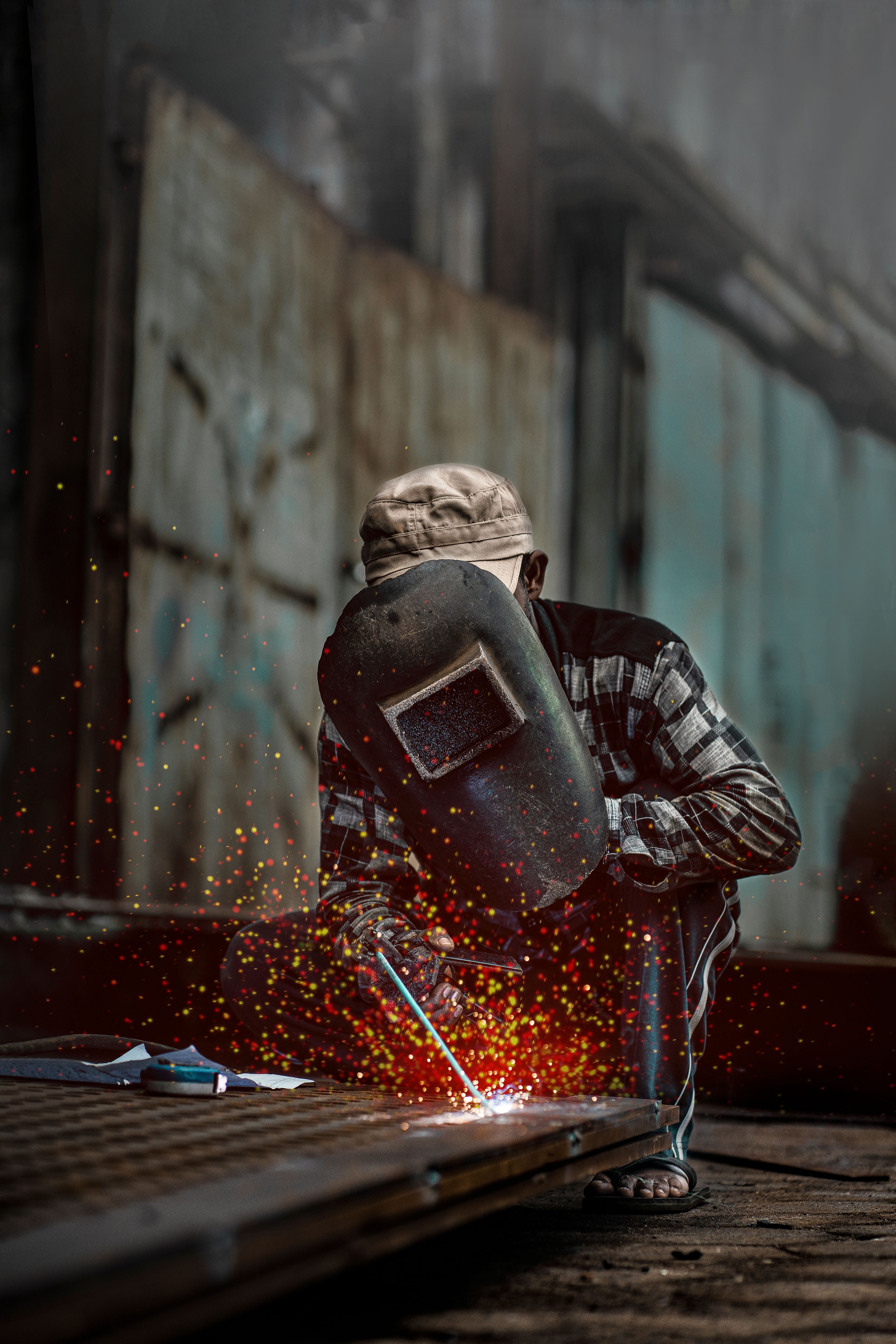 Welder in action with helmet and sparks flying in a gritty industrial setting.