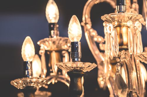Free Close-up of a luxurious crystal chandelier with glowing bulbs and teardrop decorations. Stock Photo
