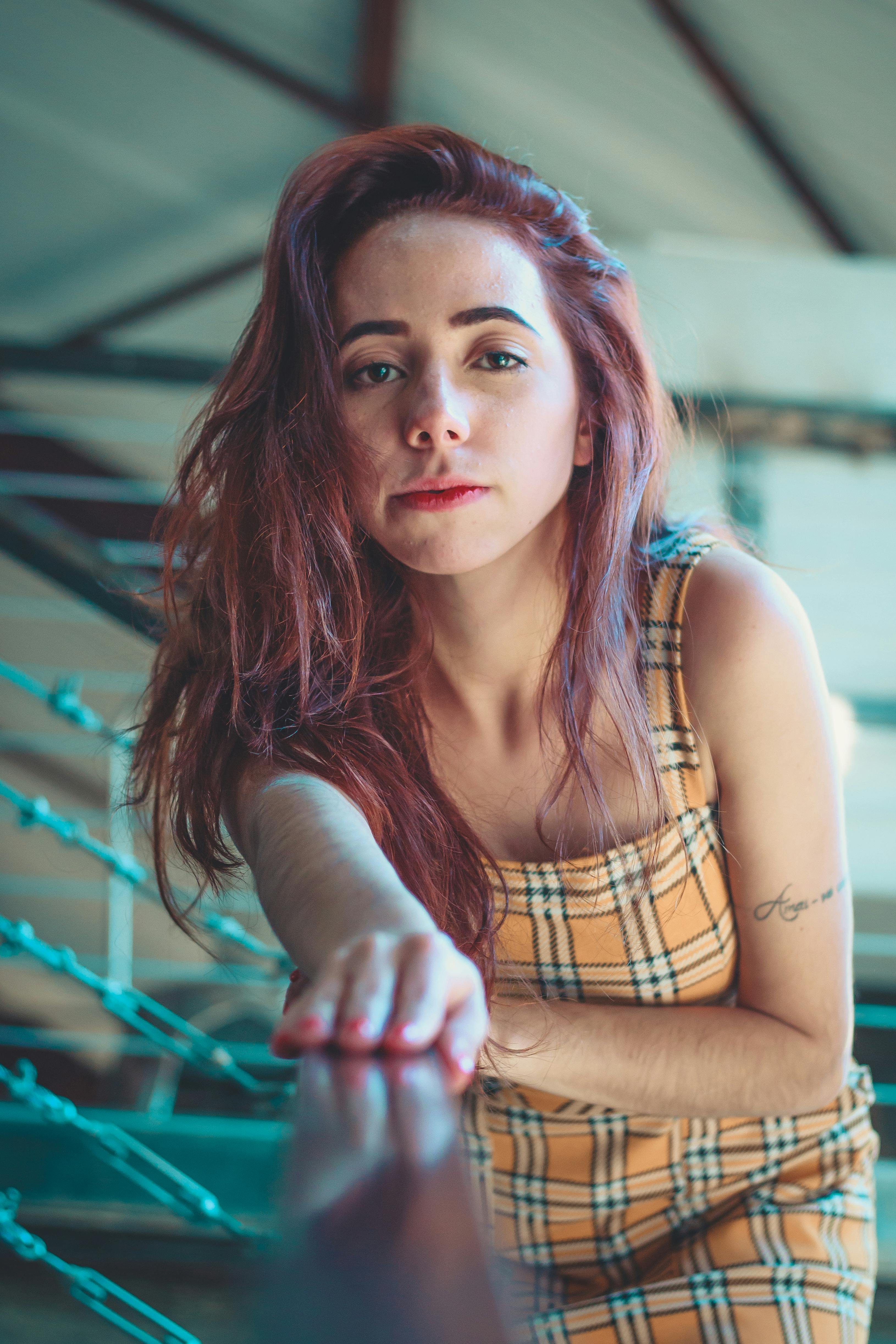 室内，一个红发女人穿着格子连衣裙，靠在栏杆上