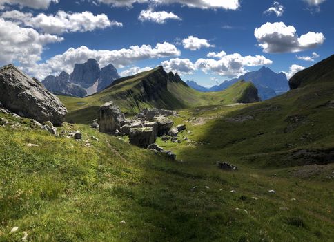 Explore the breathtaking landscapes of the Dolomites with rugged peaks and lush meadows under a summer sky.