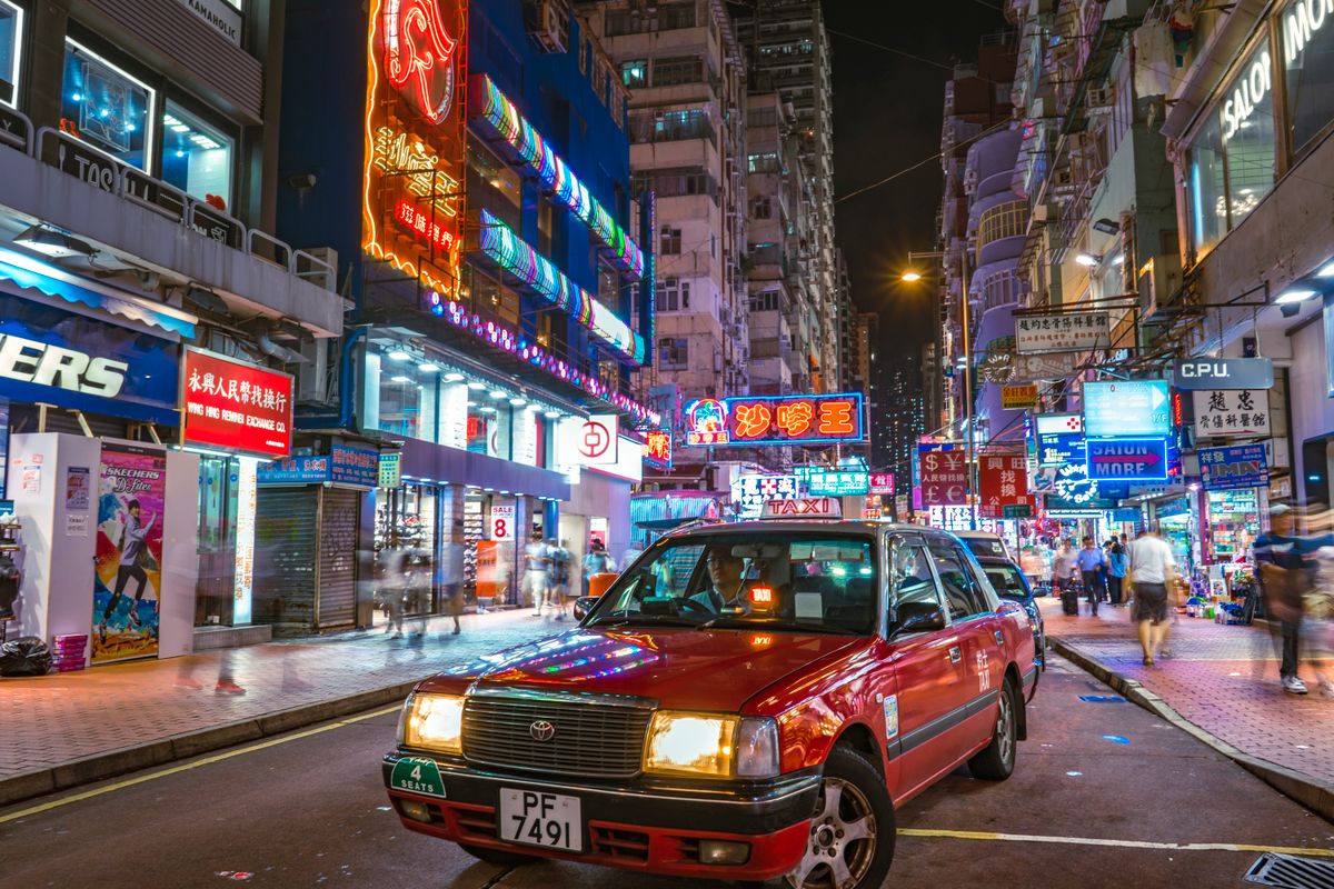 Red Hong Kong taxi at night on a neon-lit street