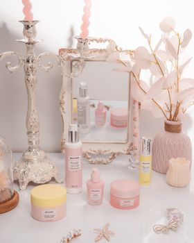 A sophisticated setup featuring pink beauty products, candelabra, and a floral vase.