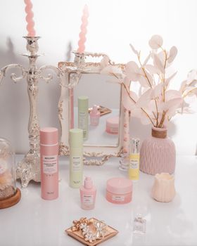 A beautifully arranged vanity with skincare products, pink decor, and a mirror.