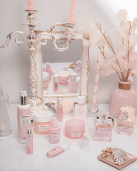 Charming arrangement of pink cosmetics with candles and a mirror, exuding elegance.
