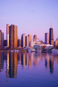 在充满活力的日落时分，芝加哥的城市天际线倒映在河面上，摩天轮也映入眼帘