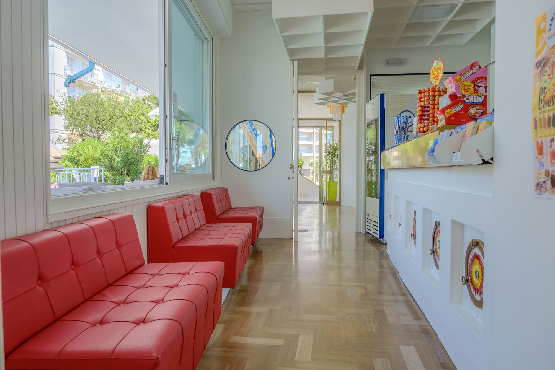 A sleek hotel corridor with red sofas, contemporary design, and a colorful candy display.