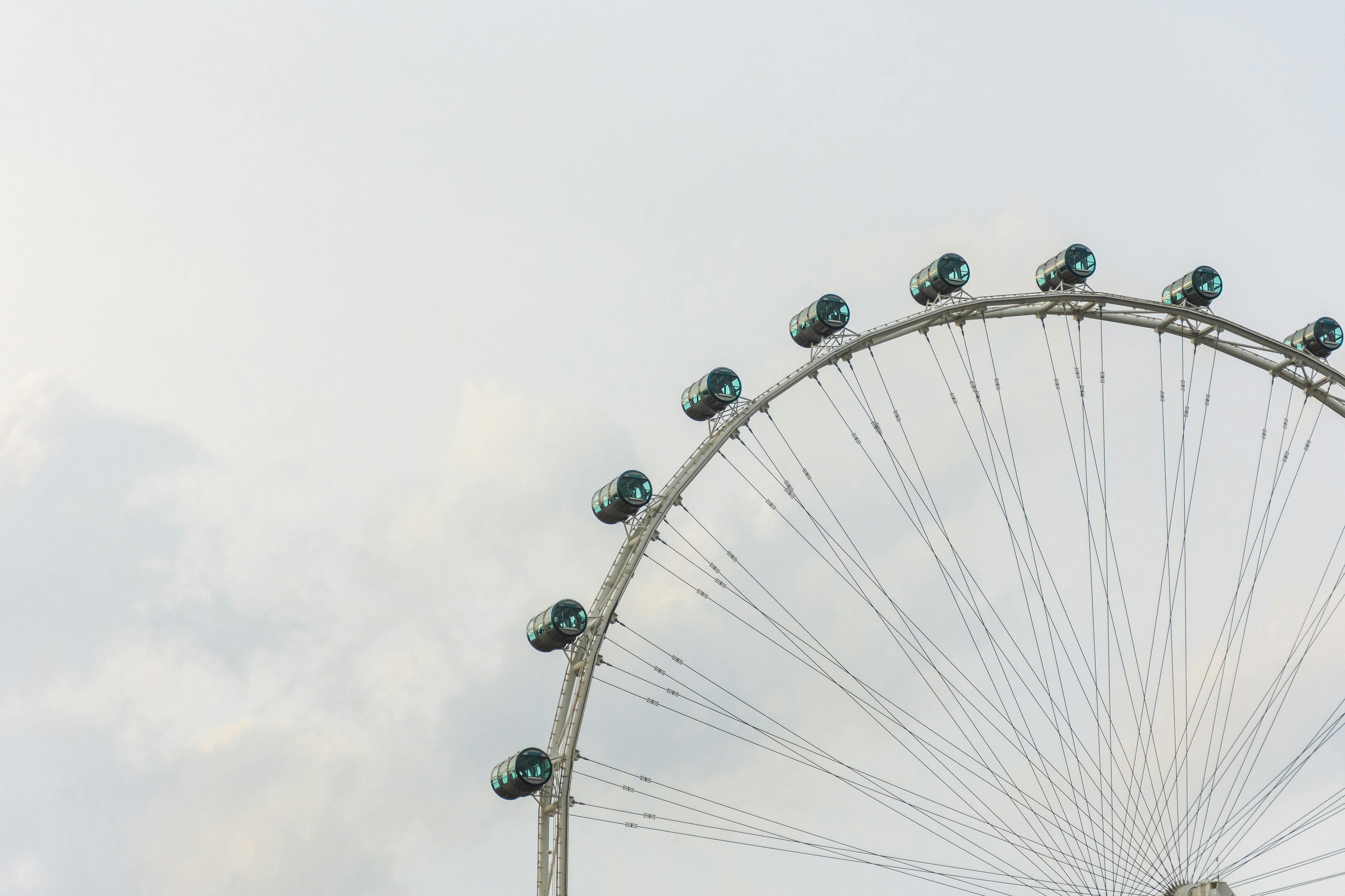 A close-up of the Singapore Flyer Ferris wheel against a cloudy sky, showcasing its engineering marvel.