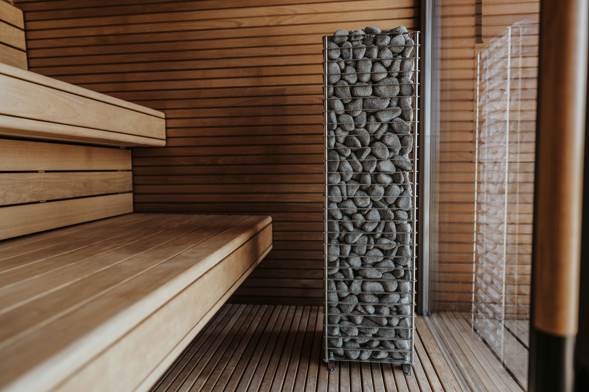 A tranquil sauna room featuring stacked rocks and wooden benches, promoting relaxation and wellness.