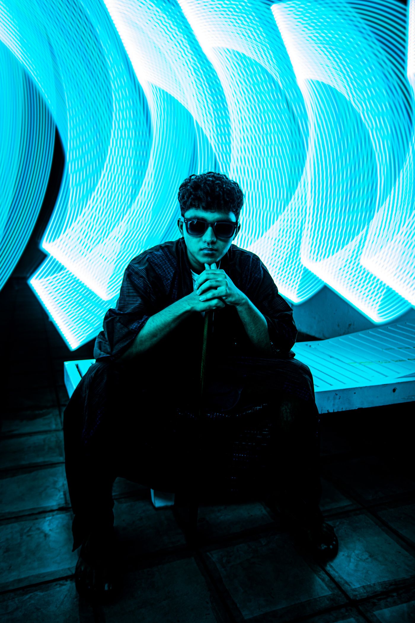 Stylish man in sunglasses beneath vibrant neon lights