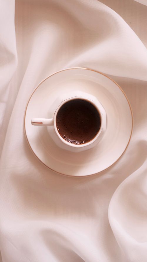 Free A top-down view of a cup of coffee set on a white cloth, creating a minimalist and cozy look. Stock Photo