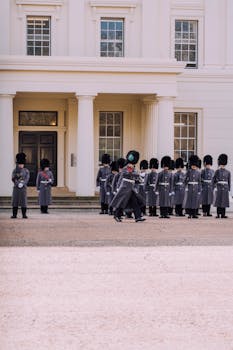 Group of royal guards in uniform lining up outside a historical building during a military inspection.