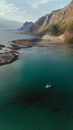 Drone view over Bodø, Norway showcasing a pristine fjord with a lone boat.