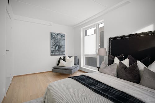 A bedroom with a white bed and black and white pillows
