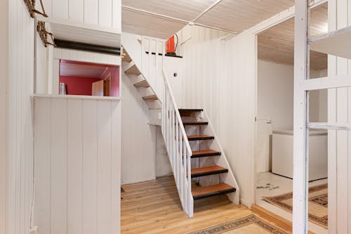 A white staircase with wooden steps and a white wall