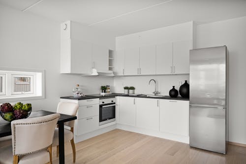 A white kitchen with a wooden floor and a refrigerator
