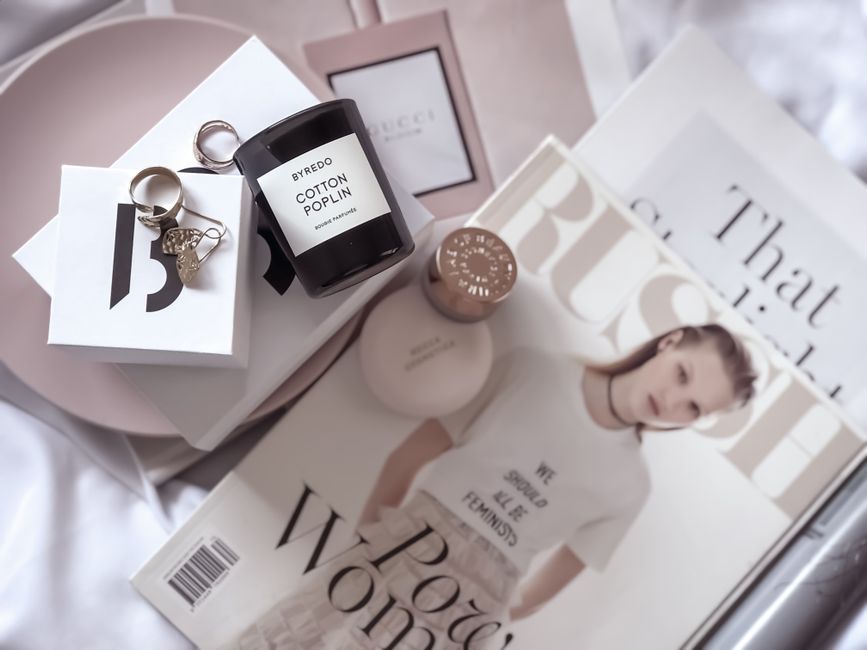 Stylish flat lay featuring fashion magazines, Byredo candle, and accessories.