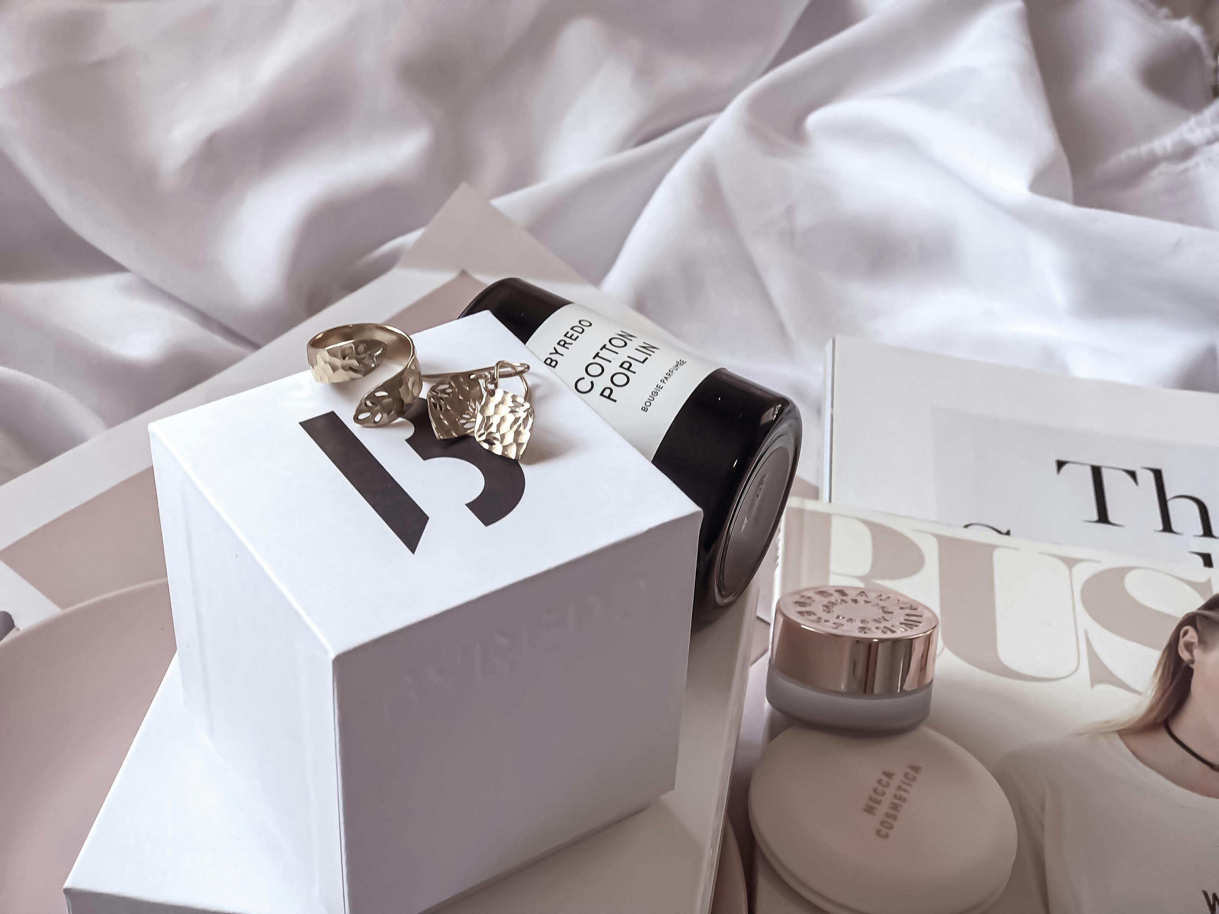 Scuffed gold lipstick and jewellery laid across a white sheet, echoing the drawer-dwelling glamour of an old beauty favourite.
