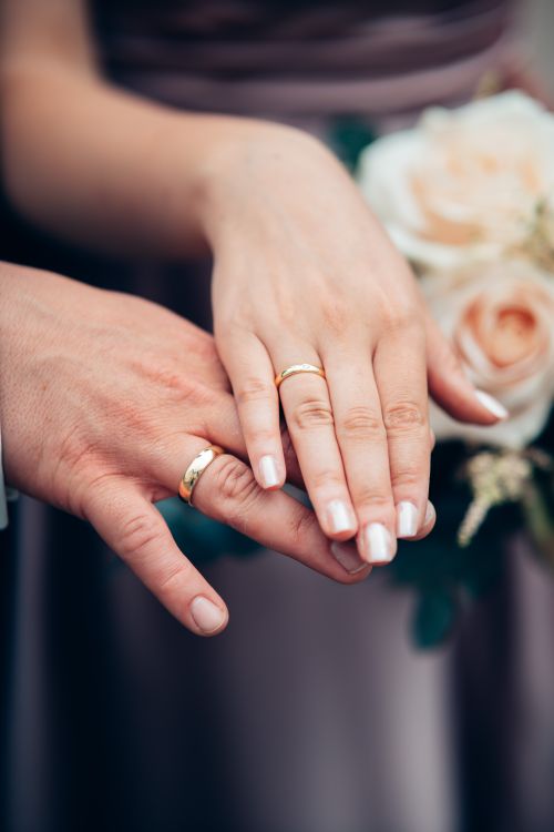 Free Close-up of a couple's hands with wedding rings, symbolizing love and unity on their special day. Stock Photo