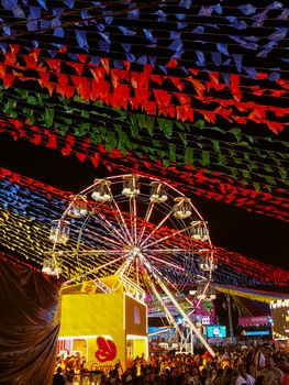 Stunning night festival scene with colorful flags and a ferris wheel in Campina Grande, Brazil.
