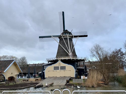 A windmill is sitting on a dock next to a body of water