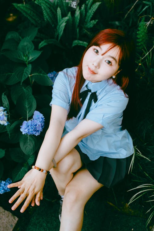 A girl in a school uniform sitting on the ground
