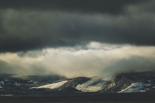 Free A moody landscape of mountains beneath a dramatic overcast sky full of thick clouds. Stock Photo