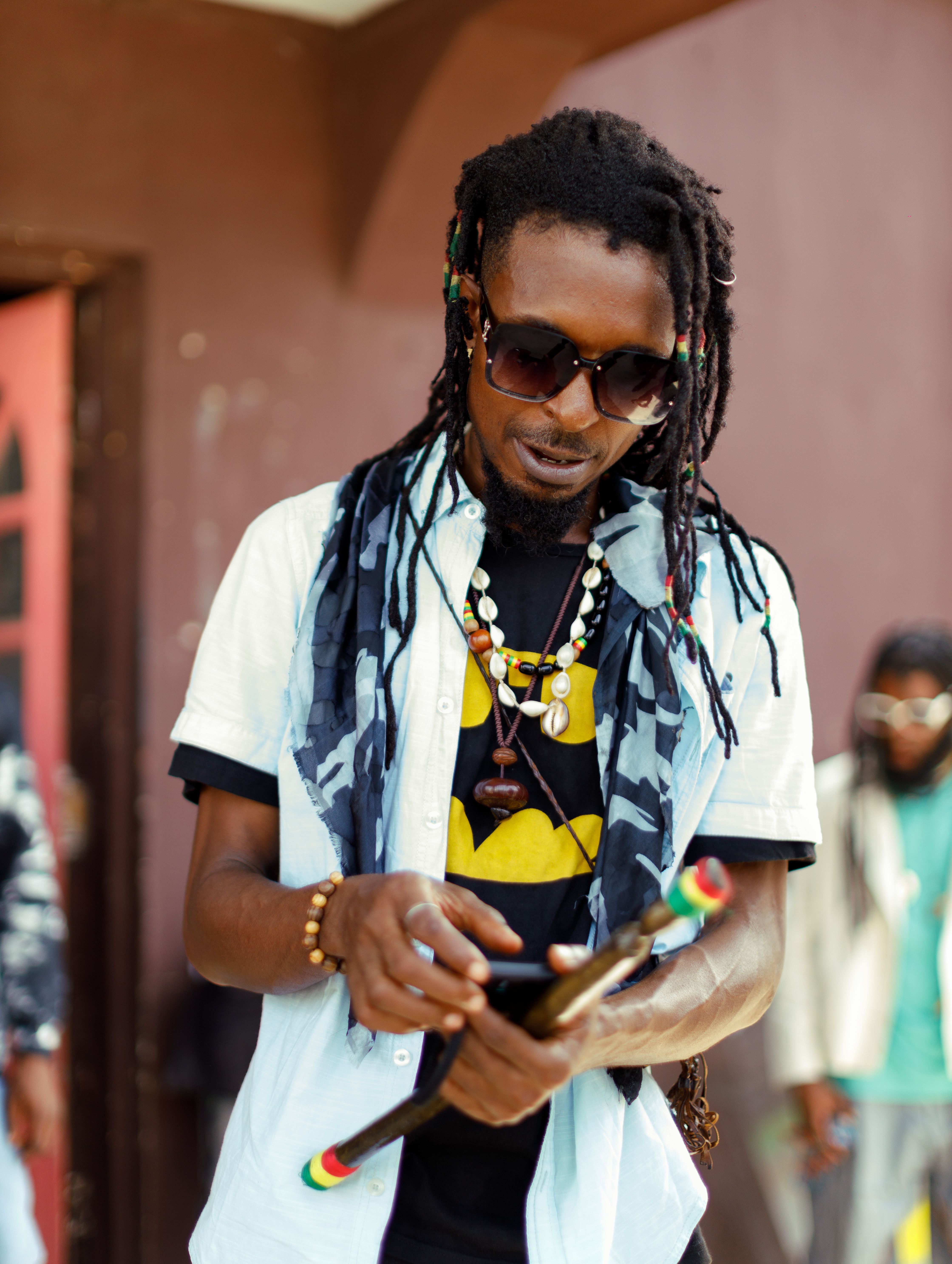 Fashionable man with dreadlocks and sunglasses in Lagos, Nigeria, showcasing modern street style.