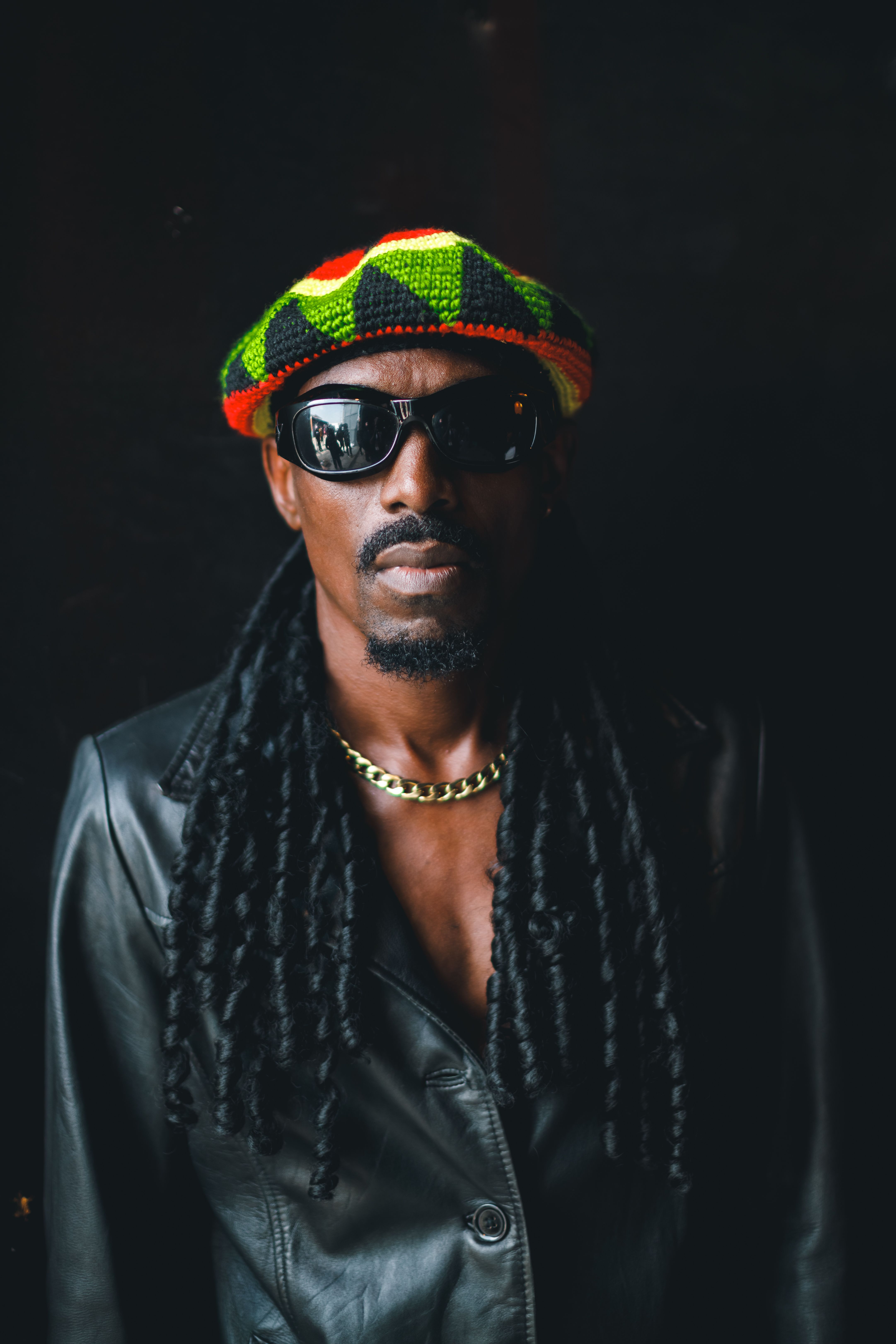 Confident man in Lagos wearing vibrant hat and sunglasses captured in a striking portrait.