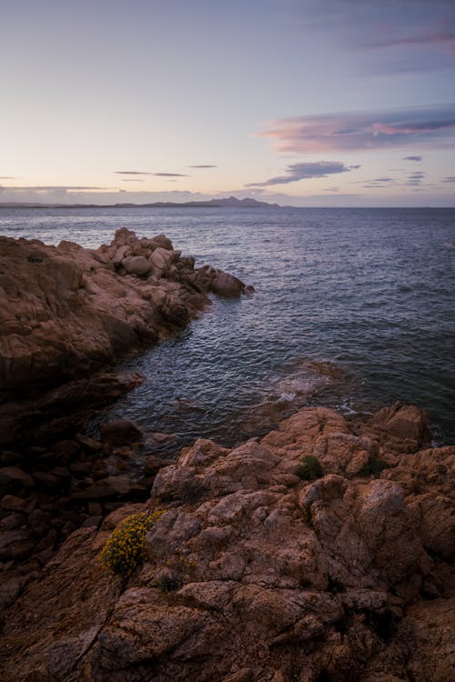 A rocky shoreline with a sunset in the background