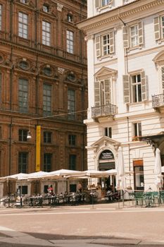 Sunlit outdoor patio in Turin, Italy with umbrellas and historic architecture.