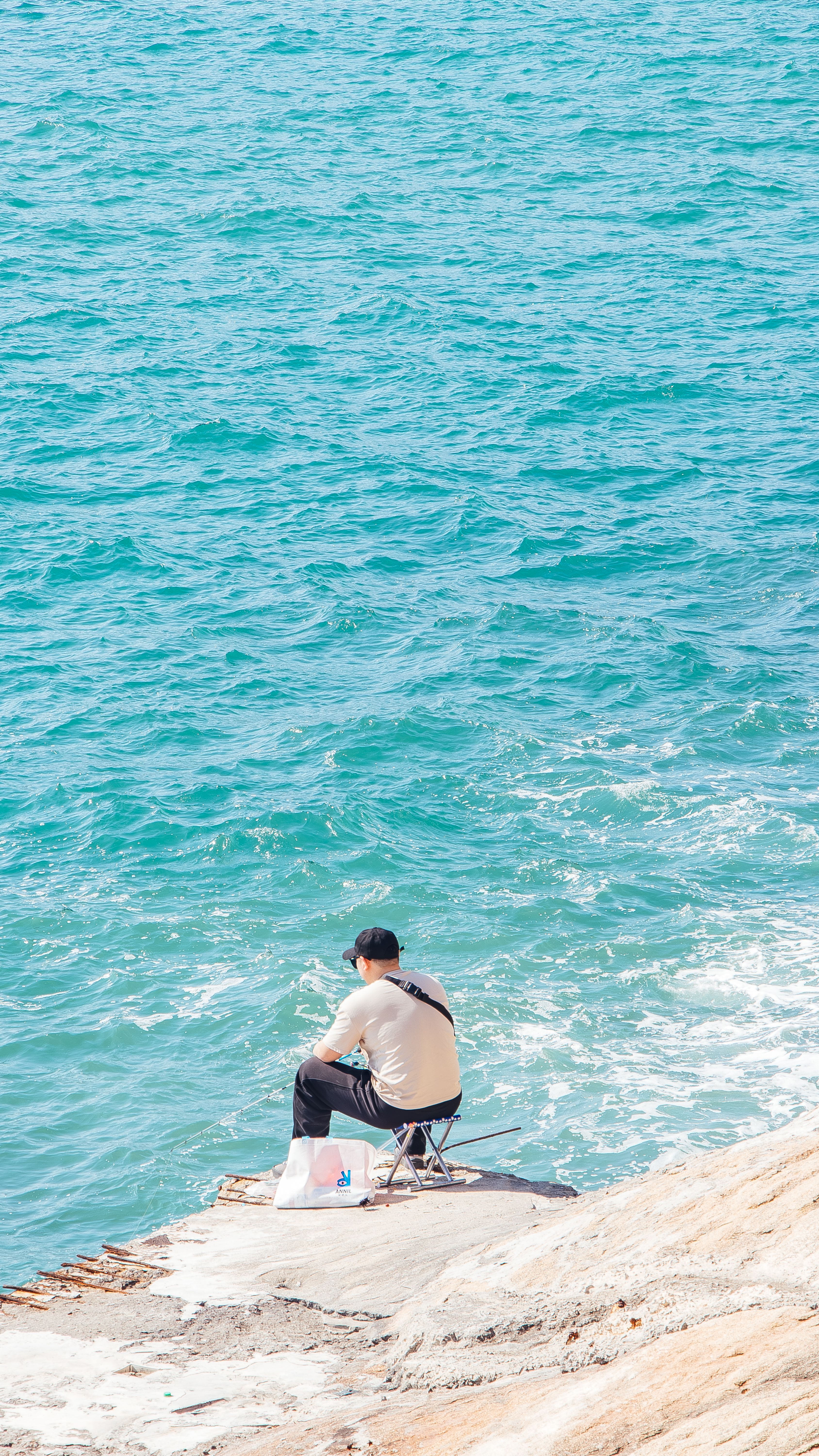 A man sitting on a rock looking out to the ocean · Free Stock Photo